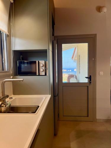 a kitchen with a microwave and a sink and a door at Gianna's Guesthouse & Cave Studio in Pylos