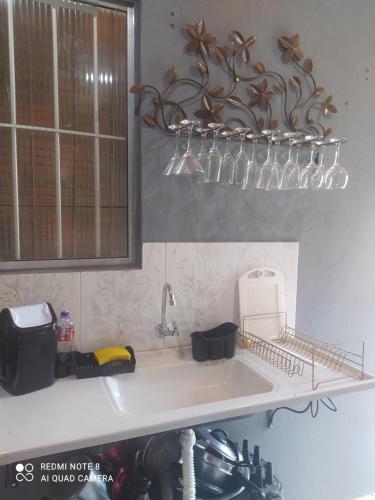 a kitchen sink with glasses on a shelf above it at Casa meu canto in Lençóis