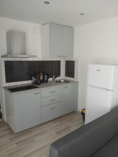Una cocina con gabinetes blancos y un refrigerador blanco. en appartement résidentiel 2 pièces, en Pierrefitte-sur-Seine