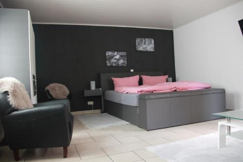 a bedroom with a bed with pink pillows and a chair at Weingut Schumacher - mit privatem Saunabereich in Sankt Aldegund