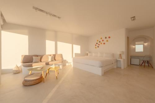 a white bedroom with a bed and a couch at Keti Hotel in Fira
