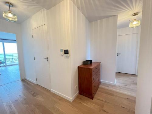 a white room with a wooden dresser and a door at Soleil couchant in Roscoff
