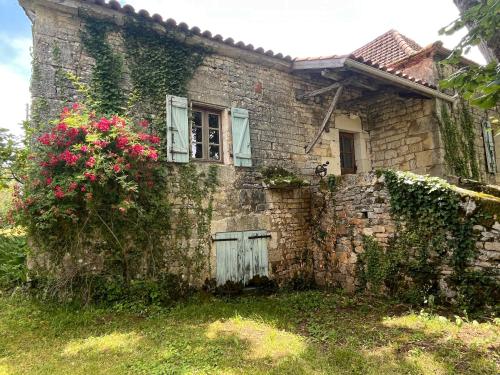 une ancienne maison en pierre avec une fenêtre et des fleurs dans l'établissement Charming Villa - Pool large Estate Piano 13p, à Esclauzels