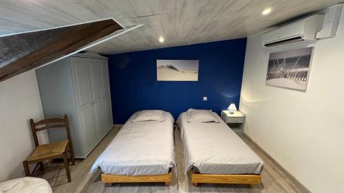 two beds in a room with a blue wall at Chambres d'hôtes Les Rozières in Le Bourdet