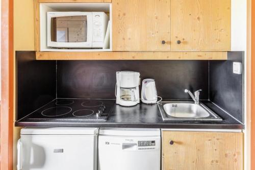 une cuisine avec un évier et un micro-ondes dans l'établissement Résidence L'Ours Blanc - maeva Home - Studio 4 Personnes Sélection MAE-8862, à Huez
