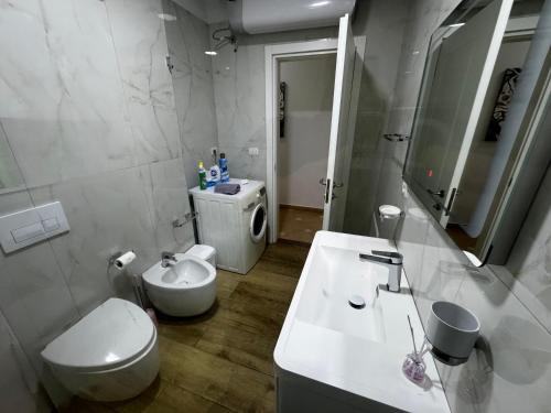 a white bathroom with a toilet and a sink at Veranda Center Apartment in Tirana