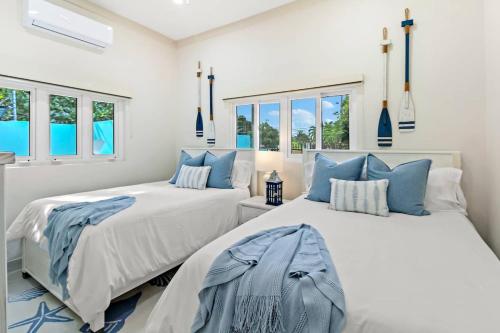 2 letti in una camera bianca con cuscini blu di NEW LUXE Caribbean Cottage in THE BAHAMAS with Canal Access! a Nassau