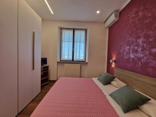a bedroom with a large bed with a pink wall at Casa Ciarpella with pool in Montegranaro