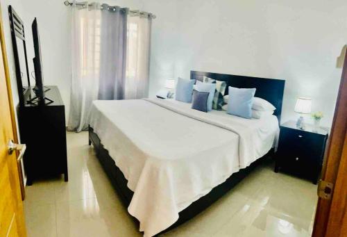 a bedroom with a large bed with blue pillows at hermosa casa en las orquídeas la romana in La Romana