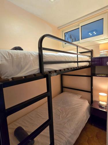 deux lits superposés dans une chambre avec fenêtre dans l'établissement Fidji - à 7min de la mer à pied, avec balcon et parking - BY Auraconciergerie, aux Lecques