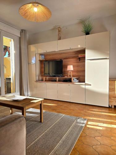 un salon avec un canapé et une télévision dans l'établissement Fidji - à 7min de la mer à pied, avec balcon et parking - BY Auraconciergerie, aux Lecques