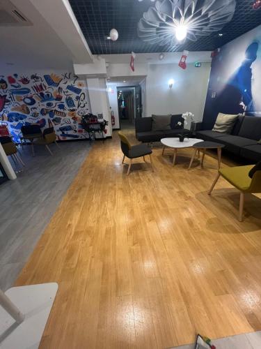 a living room with couches and chairs and a wooden floor at ibis Strasbourg Sud La Vigie in Ostwald