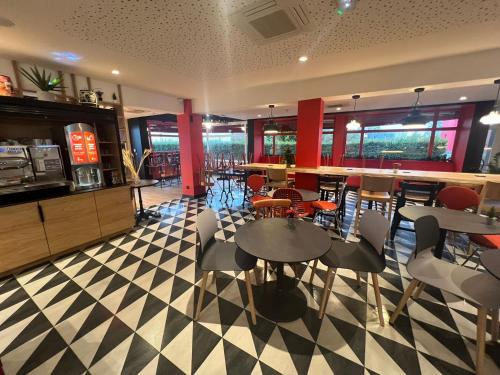 a restaurant with tables and chairs on a checkered floor at ibis Strasbourg Sud La Vigie in Ostwald