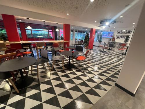 a restaurant with tables and chairs on a checkered floor at ibis Strasbourg Sud La Vigie in Ostwald