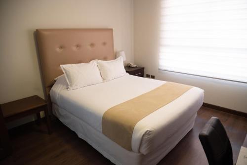 a bedroom with a large white bed with a window at Domani Hotel Boutique in Cochabamba