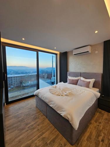 a bedroom with a large bed with a large window at MB Villas in Vrnjačka Banja