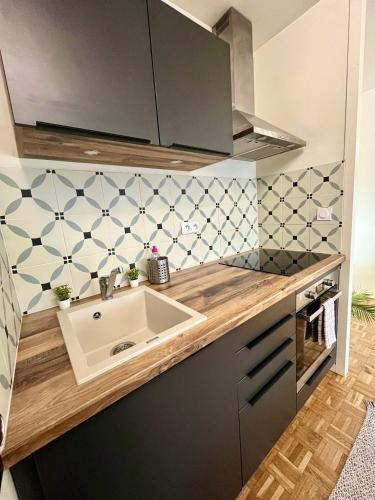 Il dispose d'une cuisine avec un évier et un mur carrelé. dans l'établissement Logement rénové proche centre-ville Lyon, à Villeurbanne