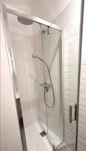 une douche avec une porte vitrée dans une salle de bain dans l'établissement Duplex à la campagne et coin jardin, à Savasse