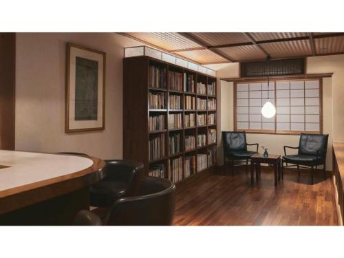 a library with two chairs and a table and bookshelves at Ryokan Akebono - Vacation STAY 91891v in Saga