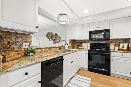 a kitchen with white cabinets and black appliances at Sunset Sanctuary at Reef Club in Clearwater Beach