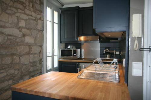 une cuisine avec des armoires noires et un comptoir en bois dans l'établissement ParisInteriorsRentals - Beautiful Le Marais NOTRE DAME Appartement, à Paris