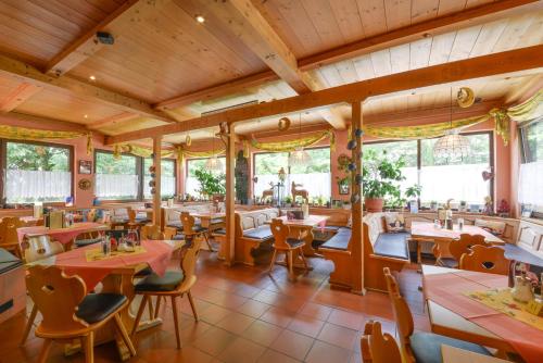 a restaurant with tables and chairs and windows at Hotel Waldhof in Hohenkammer