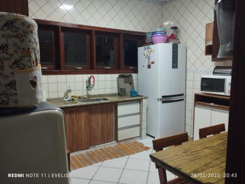 eine Küche mit einem weißen Kühlschrank und einem Tisch in der Unterkunft Casa com piscina Barê in São Sebastião