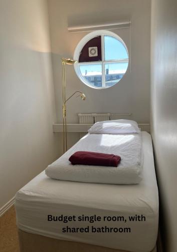 a small room with a bed with a small window at Baron's Hostel in Reykjavík