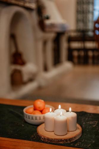two candles on a table next to a bowl of oranges at Przystanek Ropienka Leśniczówka in Ropienka