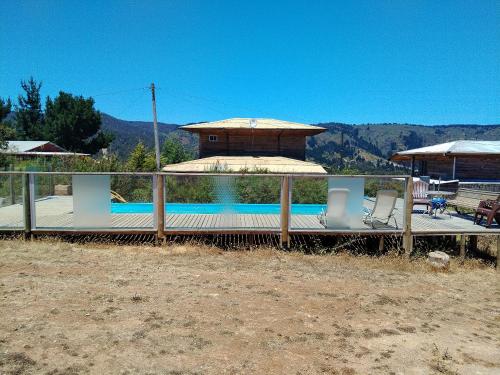 a swimming pool with two chairs and a house at Cabaña familiar y piscina valentina in Laguna Verde
