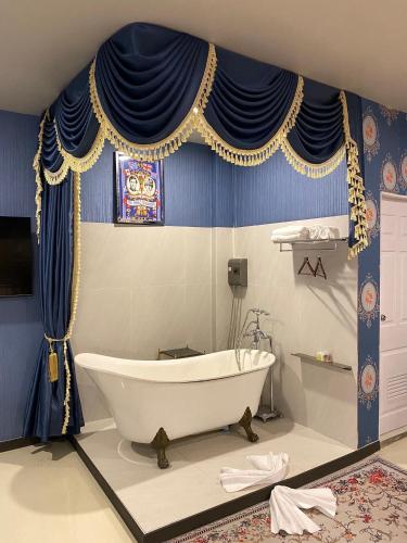 a bath tub in a bathroom with blue and yellow curtains at Duck House Hostel & Resort Khon Kaen in Ban Pet