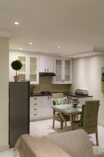 a kitchen with white cabinets and a table with chairs at Meraki Country Manor in Lanseria