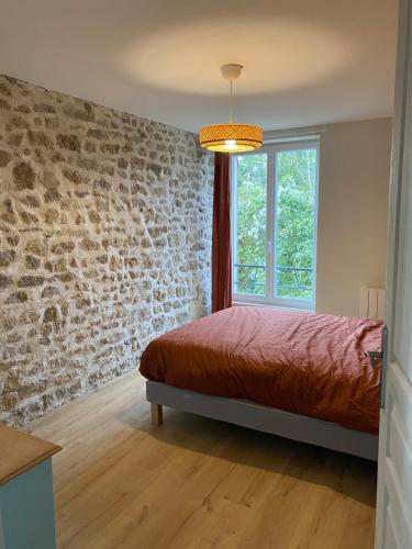 une chambre avec un lit et un mur de briques dans l'établissement La Grange d 'Escrennes, à Escrennes
