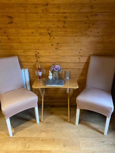 two chairs and a table with flowers and wine glasses at Crabmill glamping bewdley in Bewdley