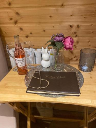 a table with a menu and a bottle of wine and flowers at Crabmill glamping bewdley in Bewdley