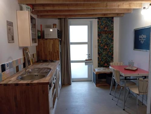 une cuisine avec un évier, une table et une fenêtre dans l'établissement Hébergement dans village de bord de Loire, à La Possonnière