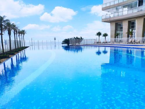 a swimming pool with palm trees in front of a building at Book Santos - Unlimited 2611 - Studio conceito com Vista Mar in Santos