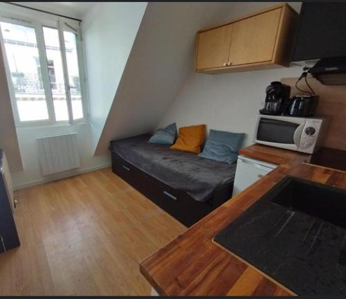 un petit salon avec un canapé et un micro-ondes dans l'établissement Cocon avec vue imprenable - Face Gare Lille Flandres 4 PERS, à Lille