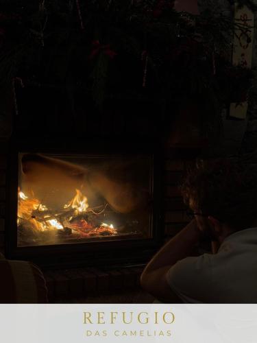 a person sitting in front of a fireplace at Refúgio das Camélias in Santana