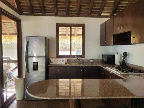 a kitchen with a stainless steel refrigerator and wooden cabinets at Las Palmeras Cambutal in Cambutal