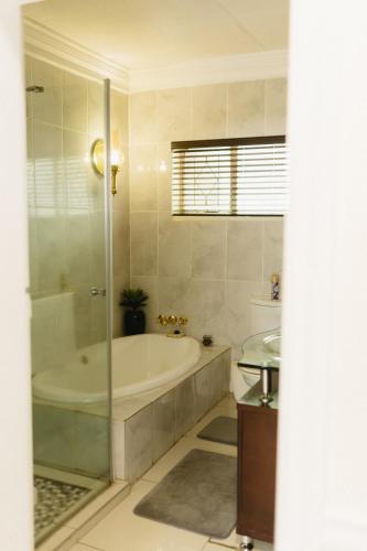 a bathroom with a bath tub and a sink at Meraki Country Manor in Lanseria