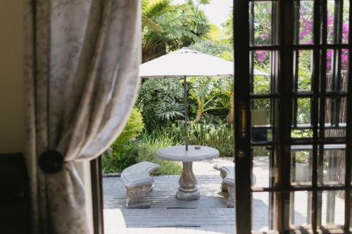 an open door to a patio with a table and an umbrella at Meraki Country Manor in Lanseria