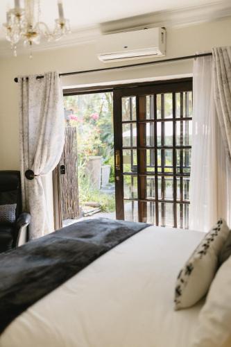 a bedroom with a bed and a large window at Meraki Country Manor in Lanseria
