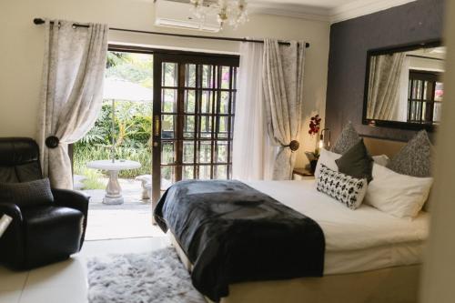 a bedroom with a bed and a chair and a window at Meraki Country Manor in Lanseria