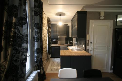パリにあるParisInteriorsRentals - Beautiful Le Marais NOTRE DAME Appartementのキッチン(黒いキャビネット、白いカウンタートップ付)