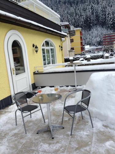 a table and two chairs on a patio with snow at Hotel Lindenhof in Bad Gastein