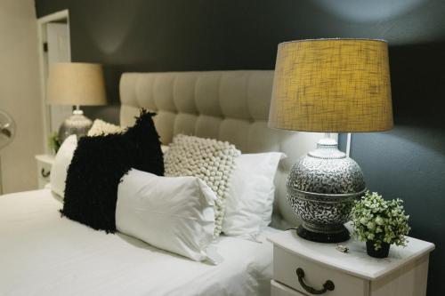 a bed with pillows and a lamp on a night stand at Meraki Country Manor in Lanseria