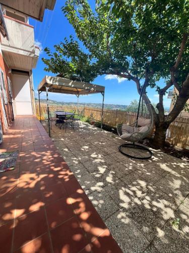 a patio with a tree and a table and chairs at Ciotti Rosella affittacamere in Acquaviva Picena