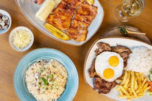 a table topped with plates of food with eggs and pasta at Hostería Paraíso in Vilcabamba