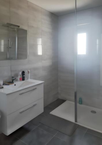 une salle de bain blanche avec une douche et un lavabo dans l'établissement Maison chaleureuse à Sully avec vue sur la montagne, à Sully